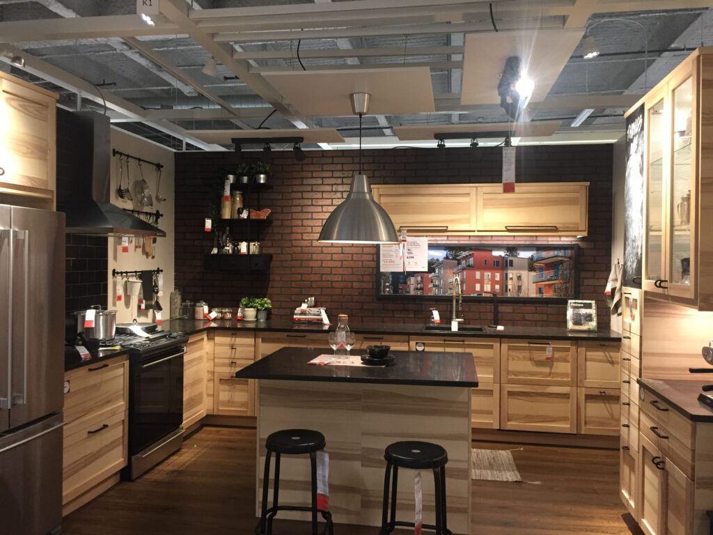 IKEA New Haven Kitchen Display. Wood grain cabinets with a dark backsplash add a spot of color and warmth.  Plenty of counter space in kitchen design